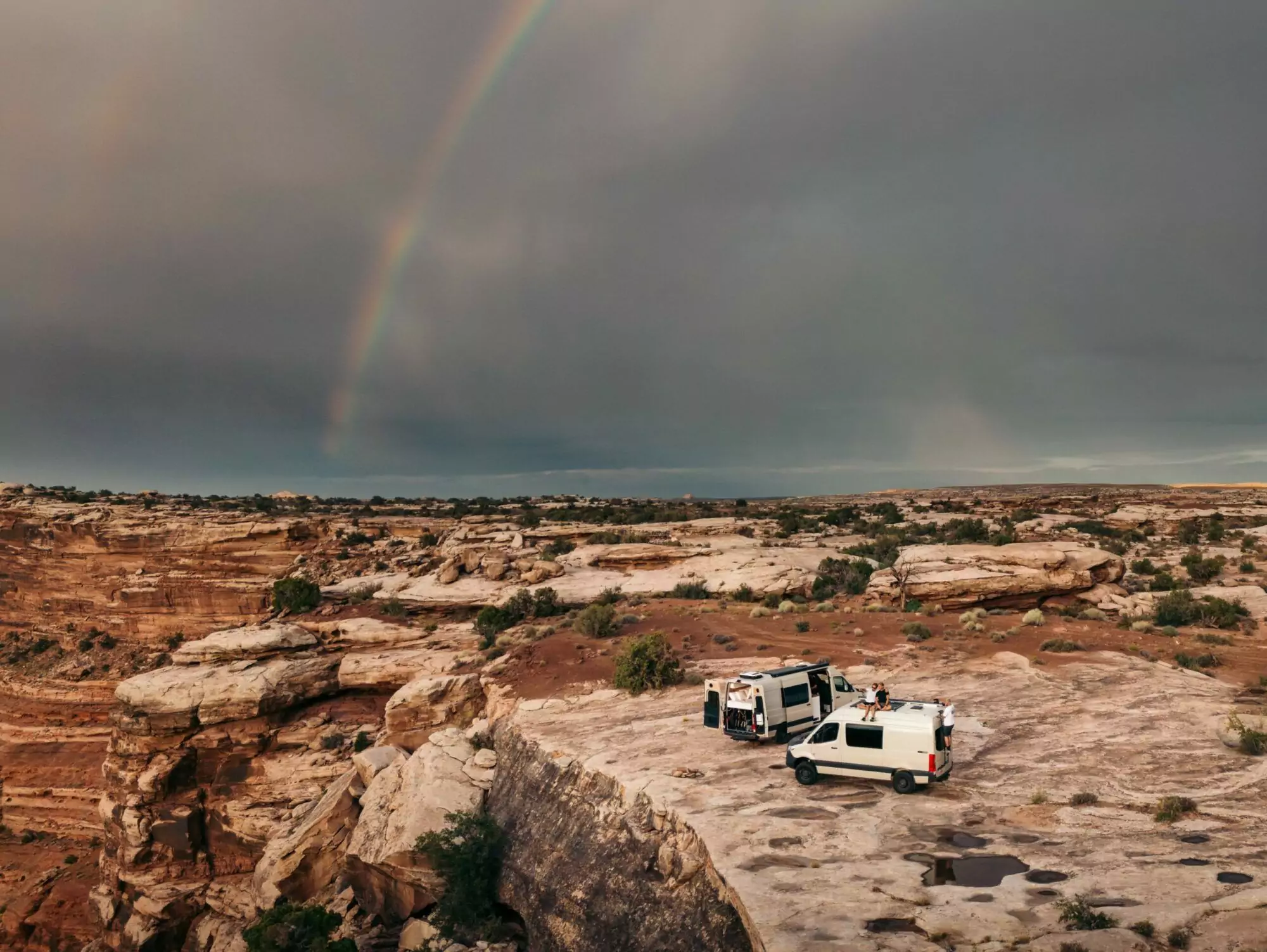 campervans parked on ridge view of landscape and rainbow